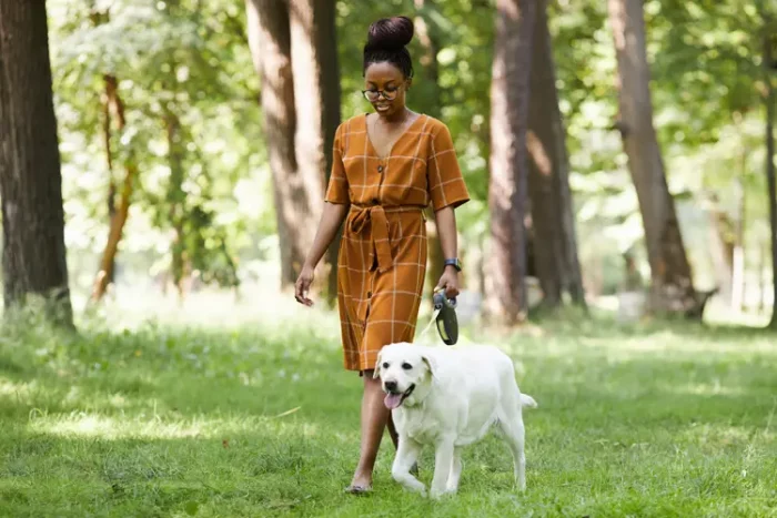 A woman walking with her service dog in a park